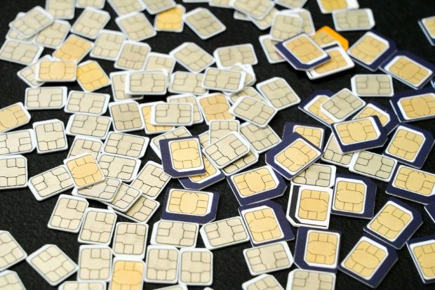 Dozens of sim cards scattered across a plain black background