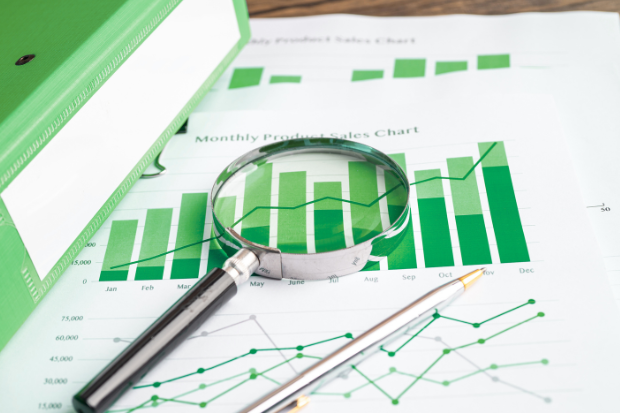 Printed out document showing graphs, with a pen and magnifying glass on top of them.